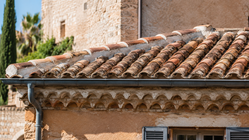 Détail d’une toiture traditionnelle à Fréjus avec tuiles canal vieillies, génoise provençale et gouttière en zinc patiné